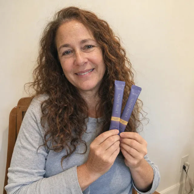 Customer holding two Orela Night Reset stick packs